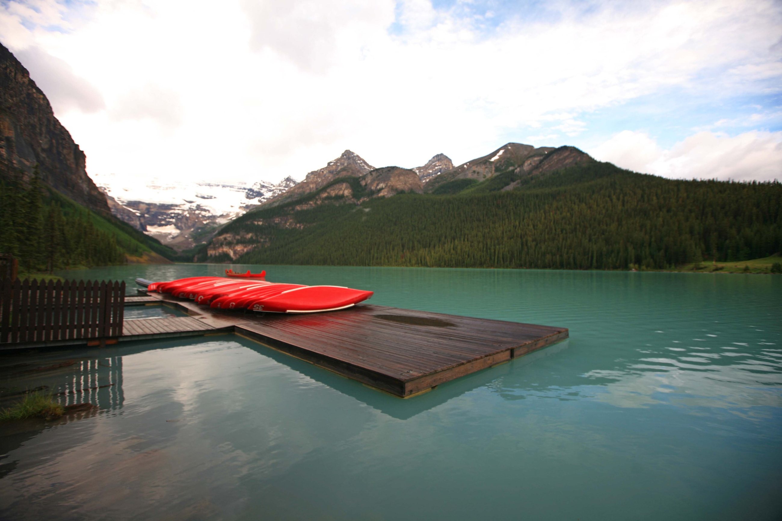 Red canoes on a dock at Lake Louise with mountains behind