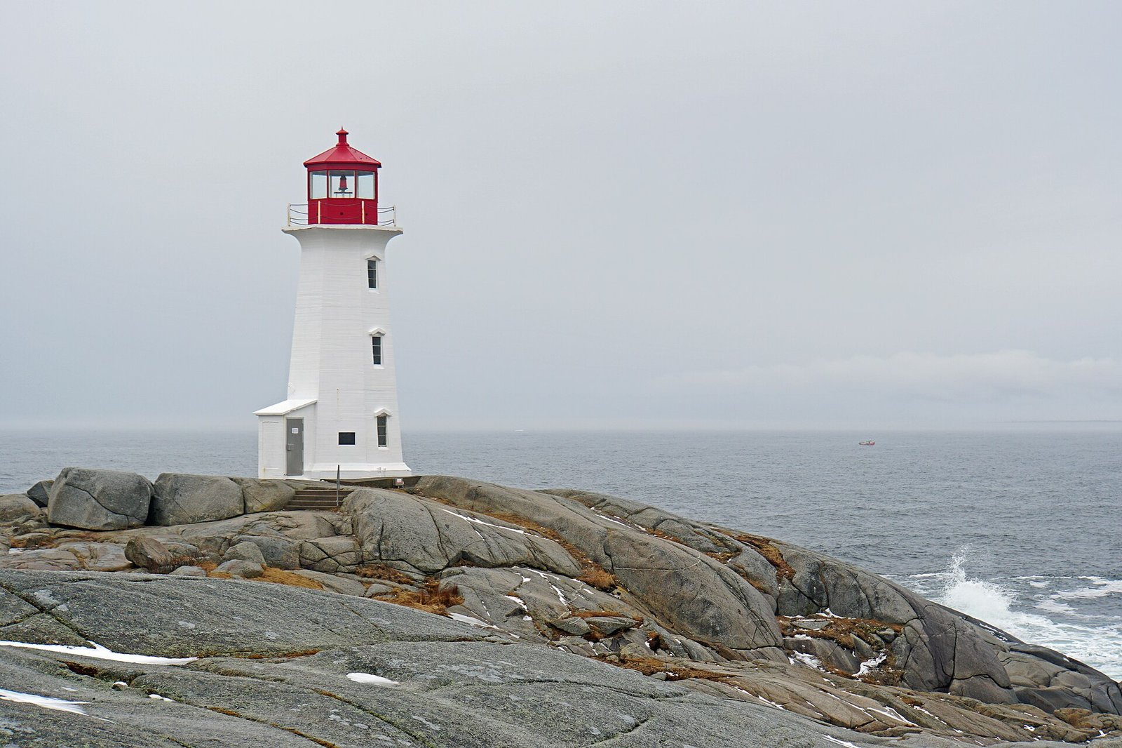 The white and red Peggy's Cove lighthouse on granite rocks by the sea