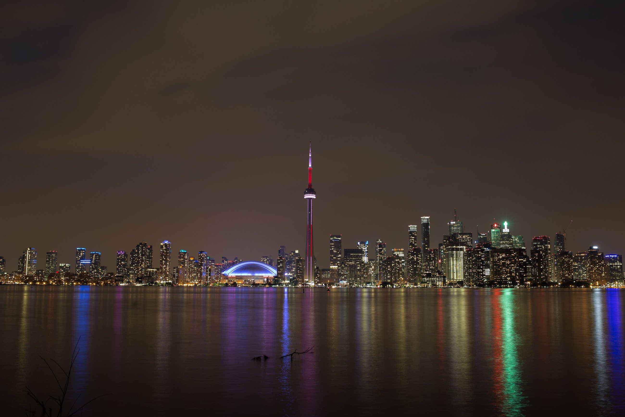Toronto's skyline and the CN Tower lit up at night across the water